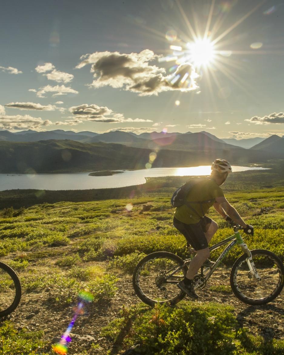 Two bikers enjoy a ride under the midnight sun near Fish Lake